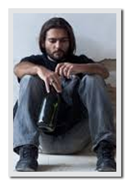 Man sitting on the floor drinking from a bottle.