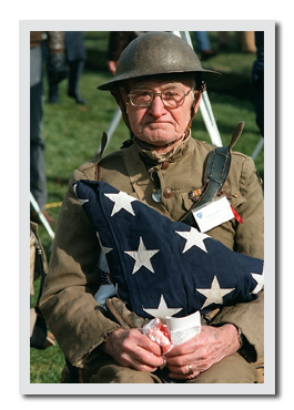 Elderly veteran holding folded flag.