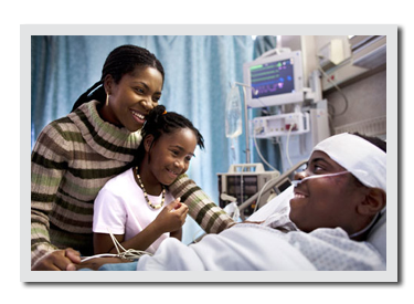 Man laying in hospital with family bedside.